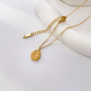 Close-up of 18K gold rose pendant necklace on white ceramic with K18 hallmark detail