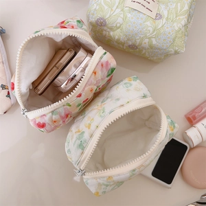 Detailed top view of quilted floral makeup bag with cosmetics on soft background