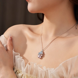 Gros plan d'un collier pendentif fleuri avec cristaux roses et bleus sur chaîne argentée