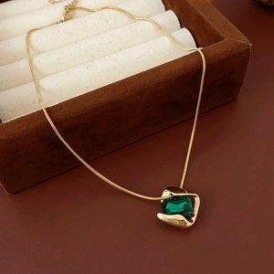 Nahaufnahme einer Vintage-Goldkette mit Smaragd auf einer luxuriösen Samtbox