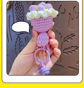 Detail of a handmade purple knitted rose keychain with green leaves and a metal ring