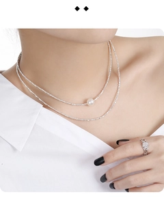 Close-up of double-layer silver necklace with pearl pendant and matching gemstone ring