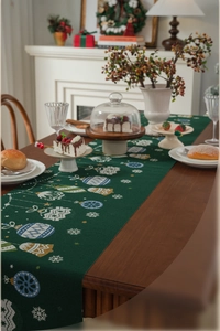 Close-up of dark green Christmas table runner with festive patterns on a wooden table