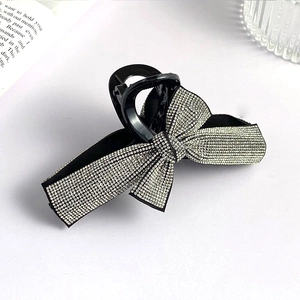 Close-up of a black hair claw clip with a large sparkling silver rhinestone bow detail