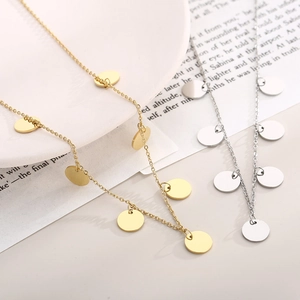 Close-up of gold and silver stainless steel necklaces with small round disc pendants