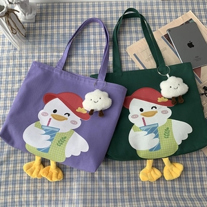 Detail of canvas tote bag featuring 3D plush duck feet and cloud charm accessory