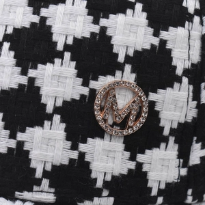Detailed macro view of houndstooth fabric with a sparkling crystal M logo badge