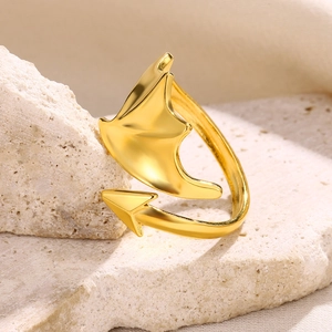 Detailed view of a gold-plated stainless steel devil wing ring on a stone pedestal