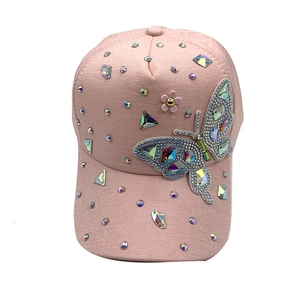 Dettaglio del cappellino rosa con patch farfalla in cristallo e strass brillanti