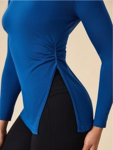 Detail view of sapphire blue long sleeve yoga top featuring side drawstring cinch design