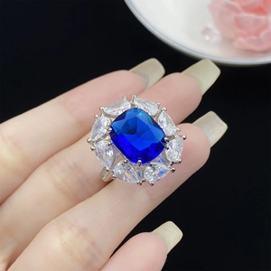 Close-up of square blue zircon ring with pear-cut accents on model hand