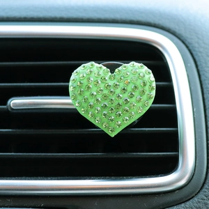 Close-up of heart-shaped car air vent clip with glittering green rhinestones