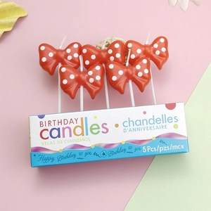 Detailed view of five red polka dot bow birthday candles with elegant party packaging