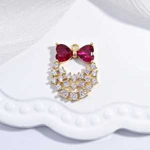 Detail of a golden bow and heart pendant with red and clear crystals on white fabric