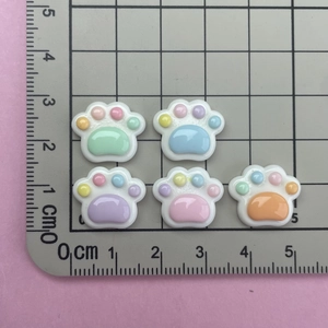 Close-up of cat paw resin charms in macaron colors on a scale mat for DIY crafts