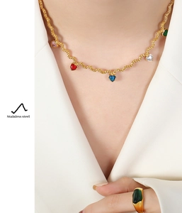 Detail of gold stainless steel heart pendant necklace and wide green stone ring on model