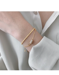 Detailed shot of double-layered gold bracelet with rhinestone cylinders on female wrist