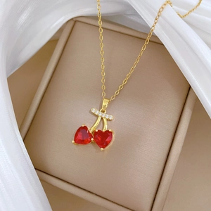 Luxurious gold cherry necklace with red heart crystals and diamonds on white silk fabric