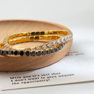 Vue détaillée de trois bracelets tennis en or avec zircons blancs et noirs sur bois