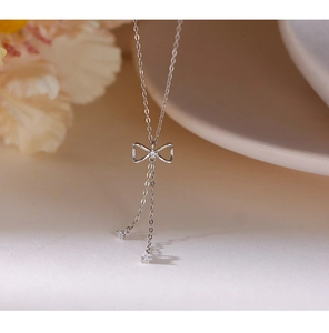 Macro shot of silver bow pendant with shimmering fringe tassels on a delicate chain
