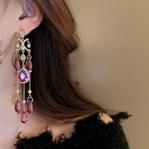 Detail of vintage drop earrings with purple crystals and pearl tassels on model
