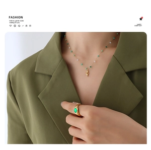 Close-up of golden tulip necklace with green beads and matching oval stone ring
