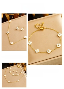 Detail of gold jewelry set featuring white flower petals and delicate chain textures
