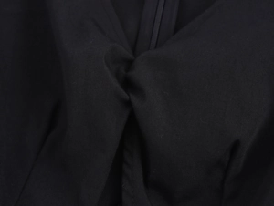 Dettaglio del tessuto nero intrecciato con design a nodo e chiusura a cerniera invisibile