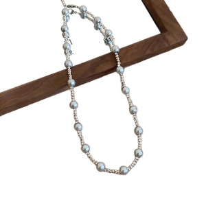 Irregular grey pearl necklace with silver textured metal beads on a white background