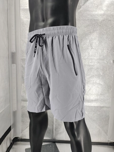 Detail view of grey quick-dry sports shorts featuring an elastic drawstring waistband and zipper pocket
