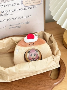 Close-up of pudding-shaped plush anime badge holder with Anya badge and cherry detail