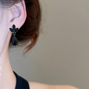 Close-up of black teardrop earrings with leaf accents on model for a refined look