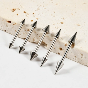 Close-up of five silver G23 titanium tongue barbells with sharp cone ends on stone