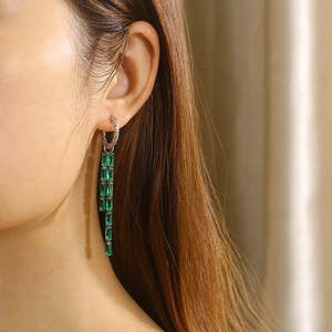 Detailed view of silver dangle earrings with multiple green baguette-cut crystals