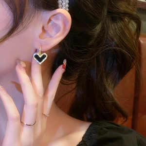 Vintage heart earrings with black enamel and diamonds worn by model in side view