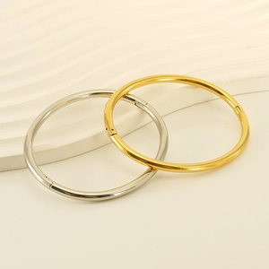 Minimalist 18K style stainless steel bangles in gold and silver on a wavy white base