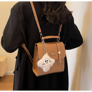 Rear view of model wearing a vintage brown PU leather backpack with a plush charm