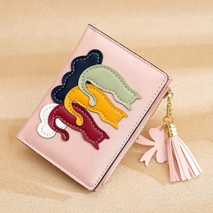 Detail of pink wallet showing stitched cat patch and decorative tassel with gold accents