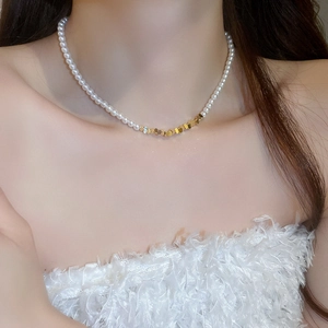 Close-up of pearl choker necklace with gold metal accents on a model's neck