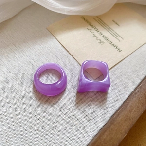Detail view of purple acrylic ring set on beige textured fabric and decorative card