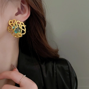 Nahaufnahme Detail von Vintage Barock Stil abstrakten Metall Gold Ohrring mit Stein.