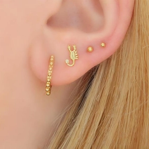 Golden S925 silver scorpion stud earring set on female model with minimalist beaded rings