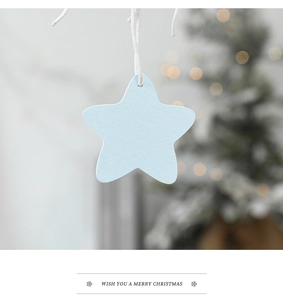 Light blue wooden star ornament with texture hanging on a blurred Christmas tree background