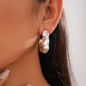 Macro shot of silver irregular water ripple earrings featuring polished metallic texture