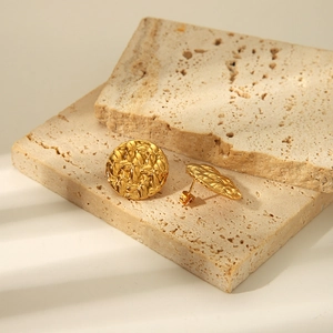Elegante goldene runde Ohrstecker mit Hammerschlag-Textur auf beigen Steinen