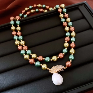 Detailed macro of 18K gold plated beaded necklace with a white teardrop pearl pendant