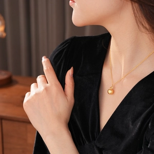 Detail of the 18k gold plated apple pendant showing matte texture on a fine chain