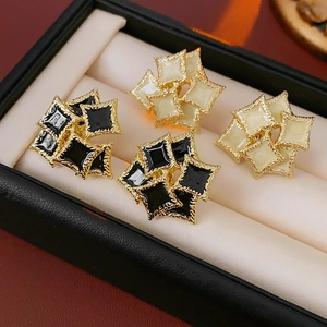 Macro detail of French vintage square enamel stud earrings in black and cream with gold trim
