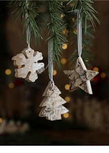Detail of wooden Christmas ornaments with bark edge hanging on pine tree branches