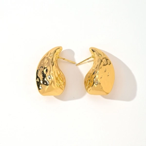 Macro detail of geometric gold earrings featuring elegant hammered textured finish